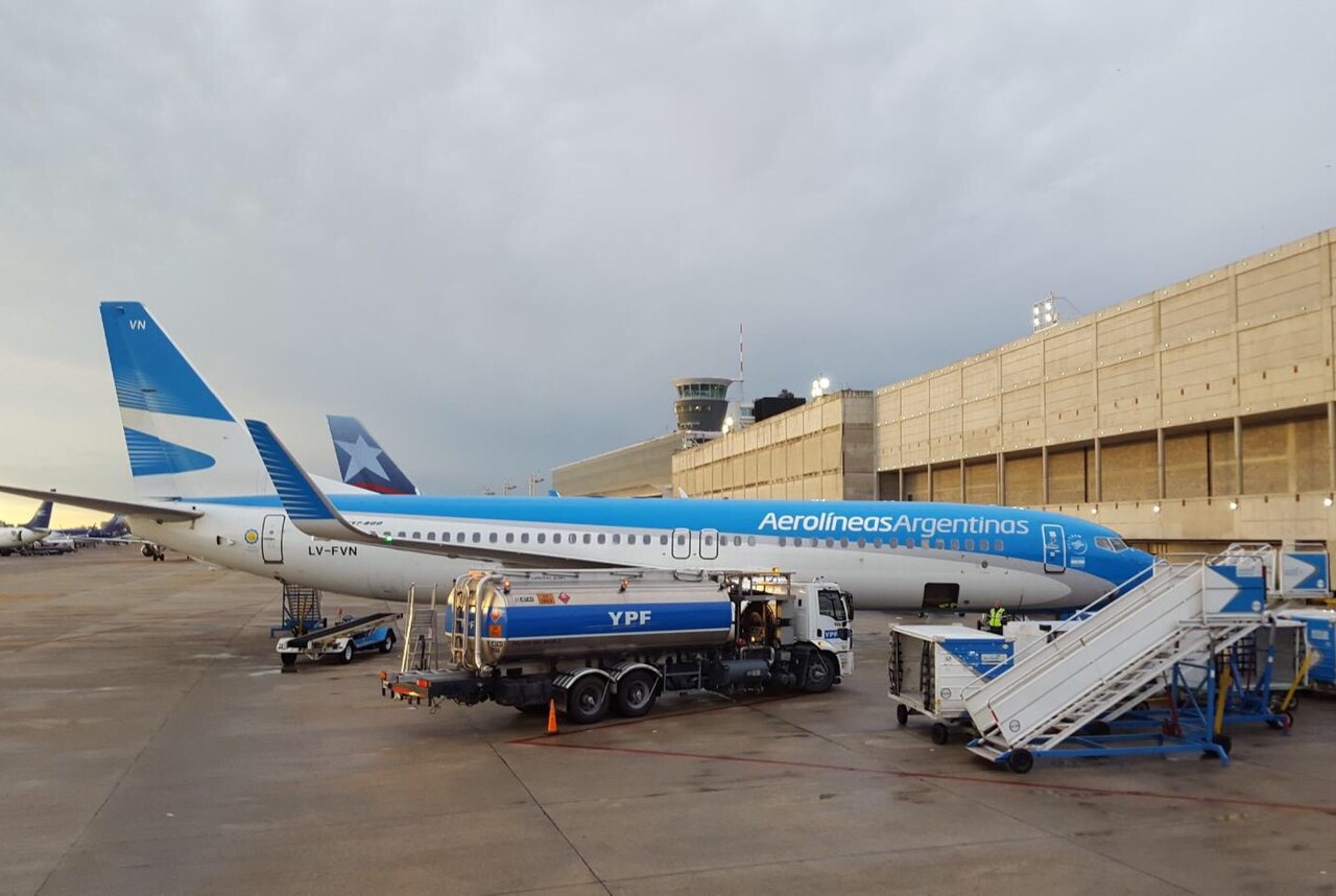 Blue and white Aerolineas Argentinas Boeing 737 parked at a terminal at Aeroparque with a YPF fuel truck in front of the fuselage under a grey sky