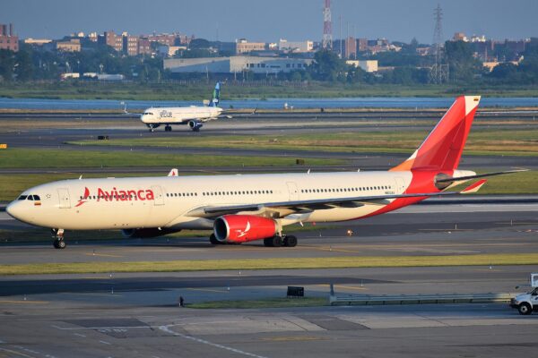 A red and white Avianca Airbus A330 taxiing at New York's JFK airport with a JetBlue jet behind it
