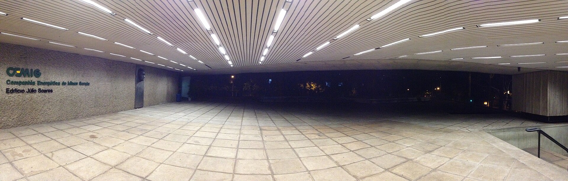 A wide night-time view of the covered entrance of a Cemig building in Belo Horizonte, with the Cemig logo and building name on a wall at left