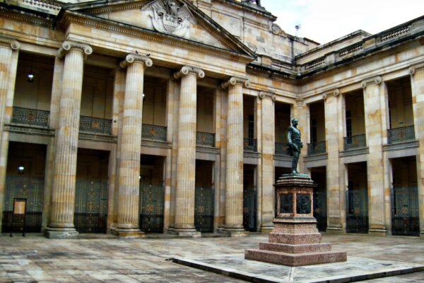 The stone colonnade and courtyard of the Capitolio Nacional in Bogota, seat of Colombia's Congress, with a bronze statue on a granite plinth