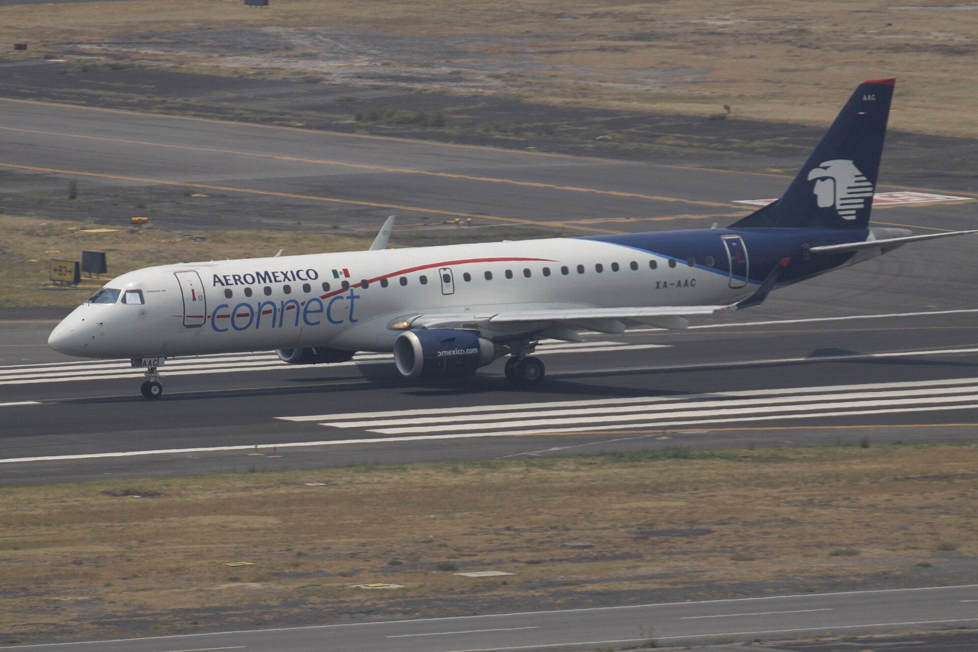 A white Aeromexico Connect Embraer 190 with a blue tail rolling on a runway