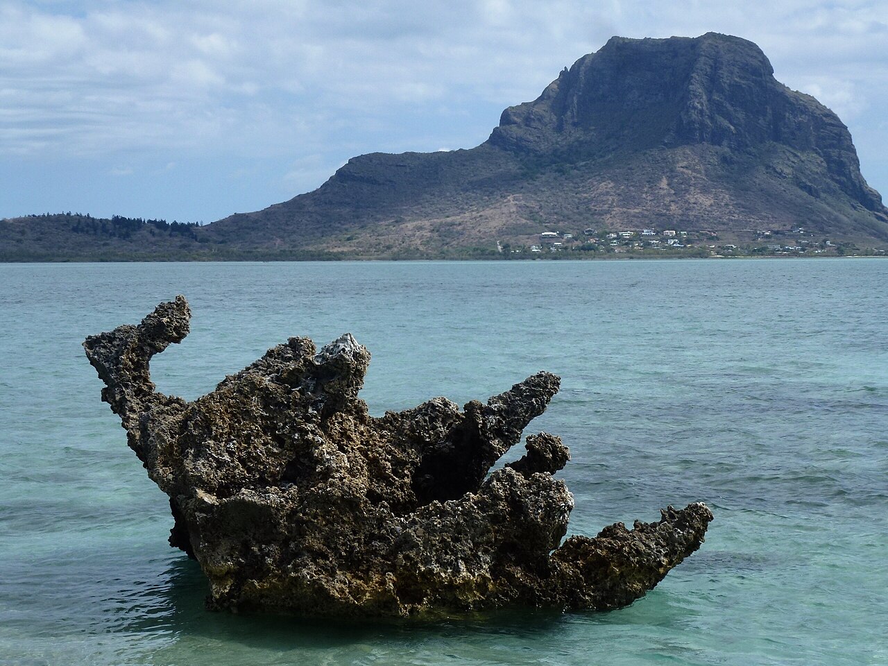A weathered coral rock in the shallow lagoon in front of Le Morne mountain in Mauritius.