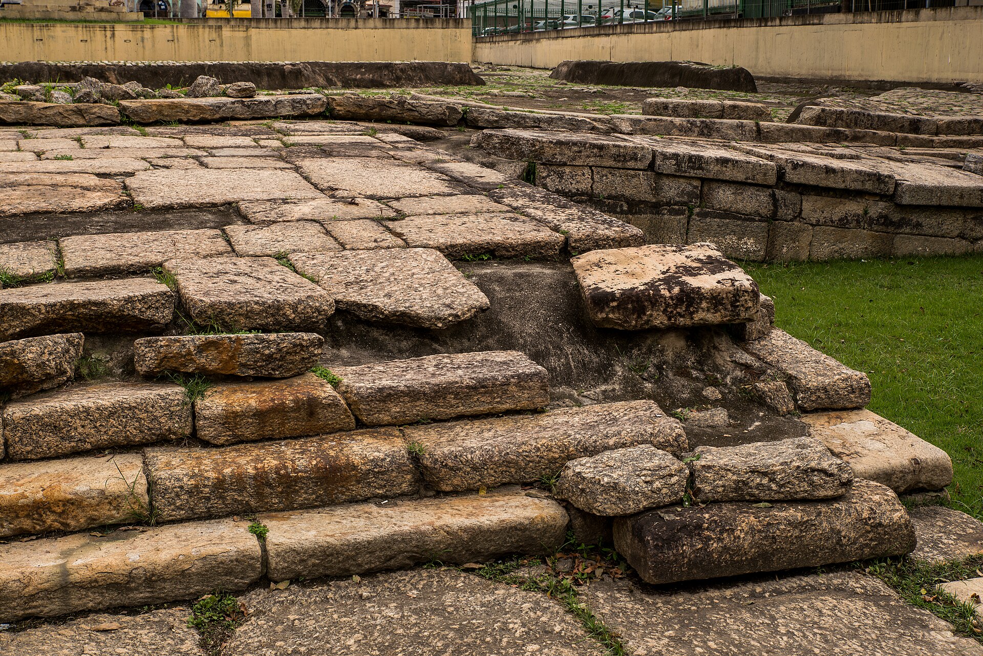 Close view of the weathered stone steps and paving of the Valongo Wharf with grass beside them