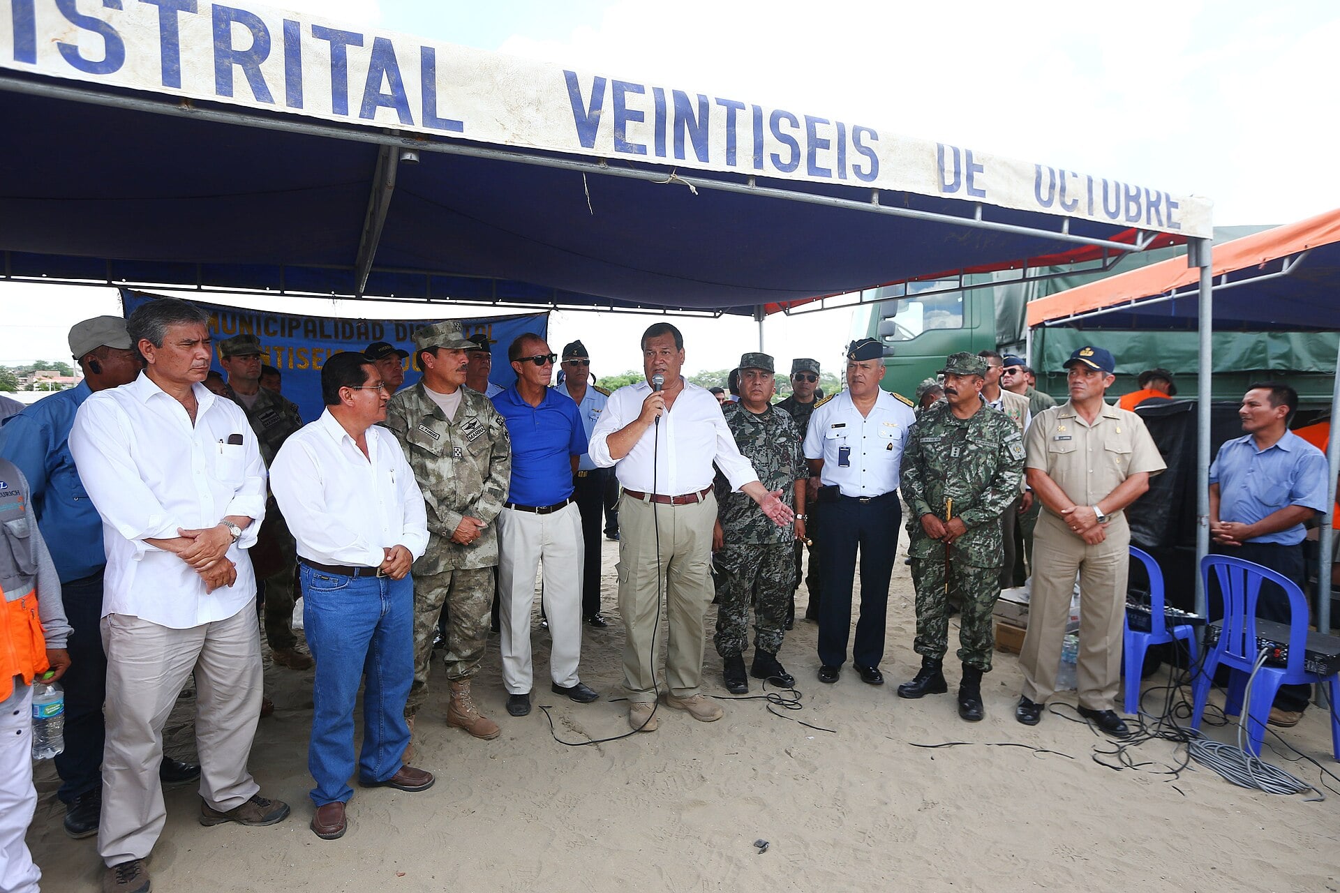 Peruvian officials and soldiers standing under a tent in Piura while a minister speaks to the group during a 2017 rain relief operation