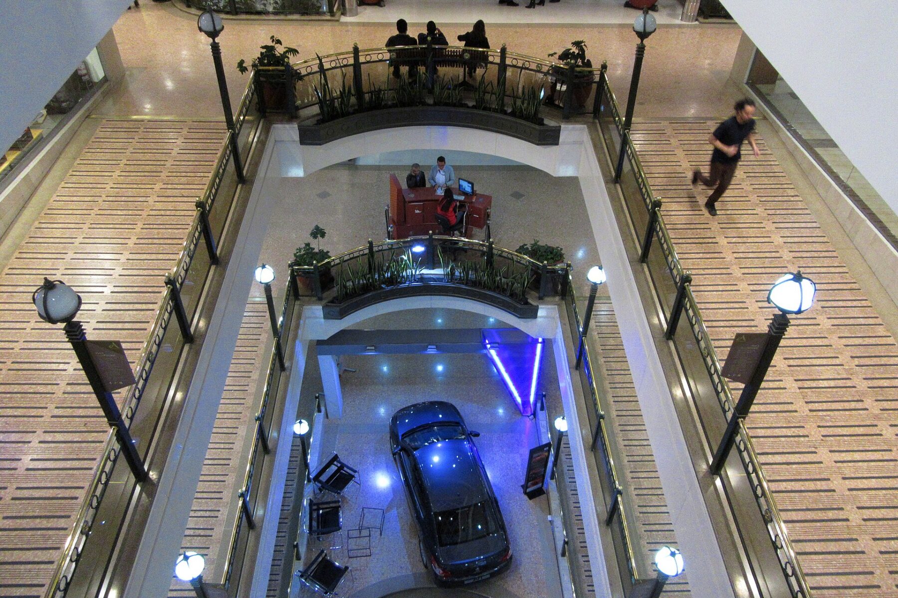 View down a multi-storey Bogotá shopping mall atrium with a car on display on the ground floor and a man walking on a gallery