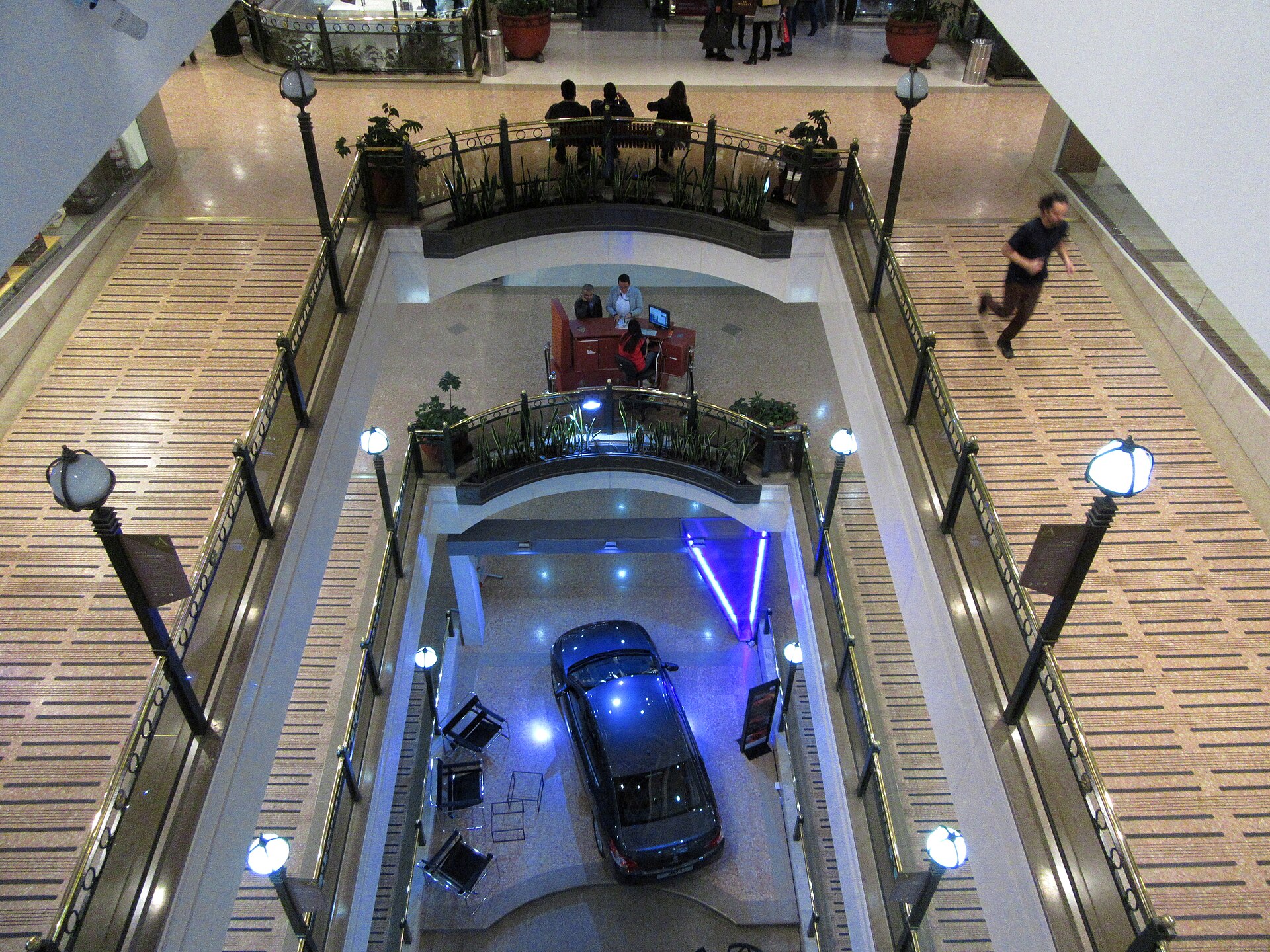 View down a multi-storey Bogotá shopping mall atrium with a car on display on the ground floor and a man walking on a gallery