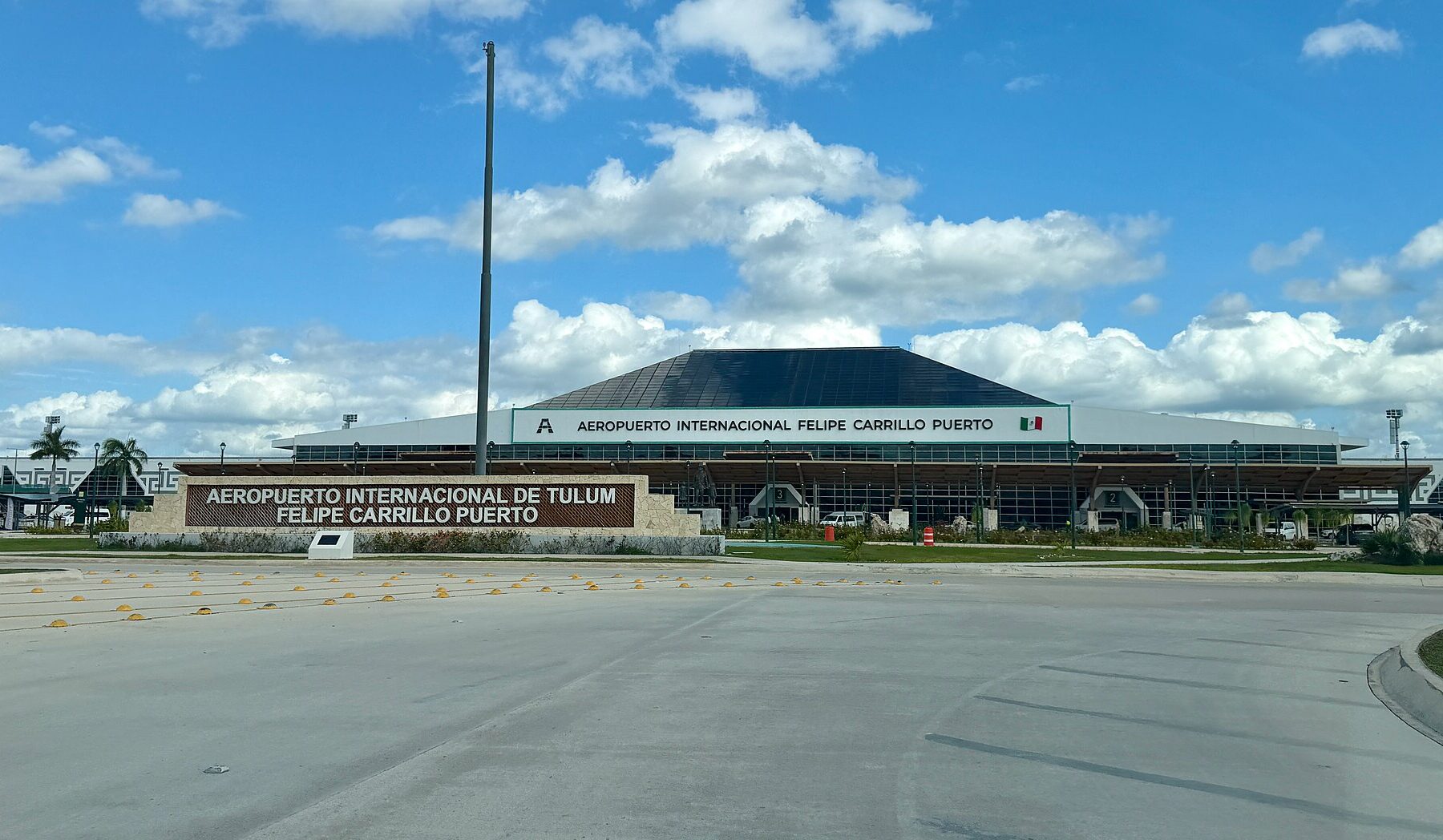 Terminal building of Felipe Carrillo Puerto International Airport in Tulum with its name sign under a blue sky