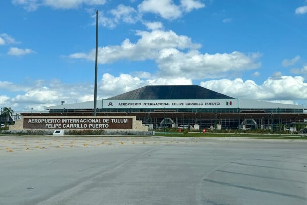 Terminal building of Felipe Carrillo Puerto International Airport in Tulum with its name sign under a blue sky