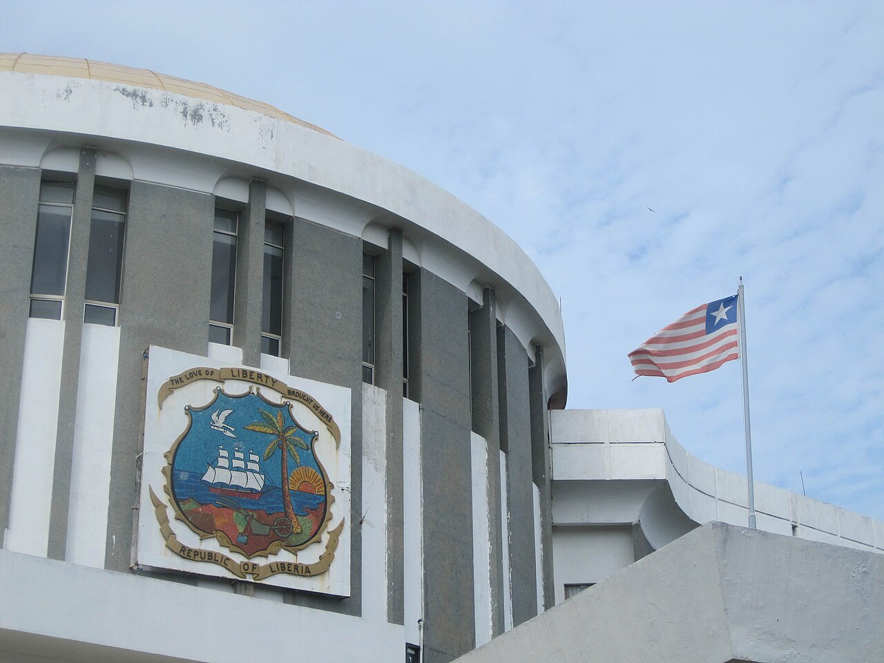 The Capitol Building in Monrovia, Liberia, with the national coat of arms on its curved facade and the Liberian flag flying beside it