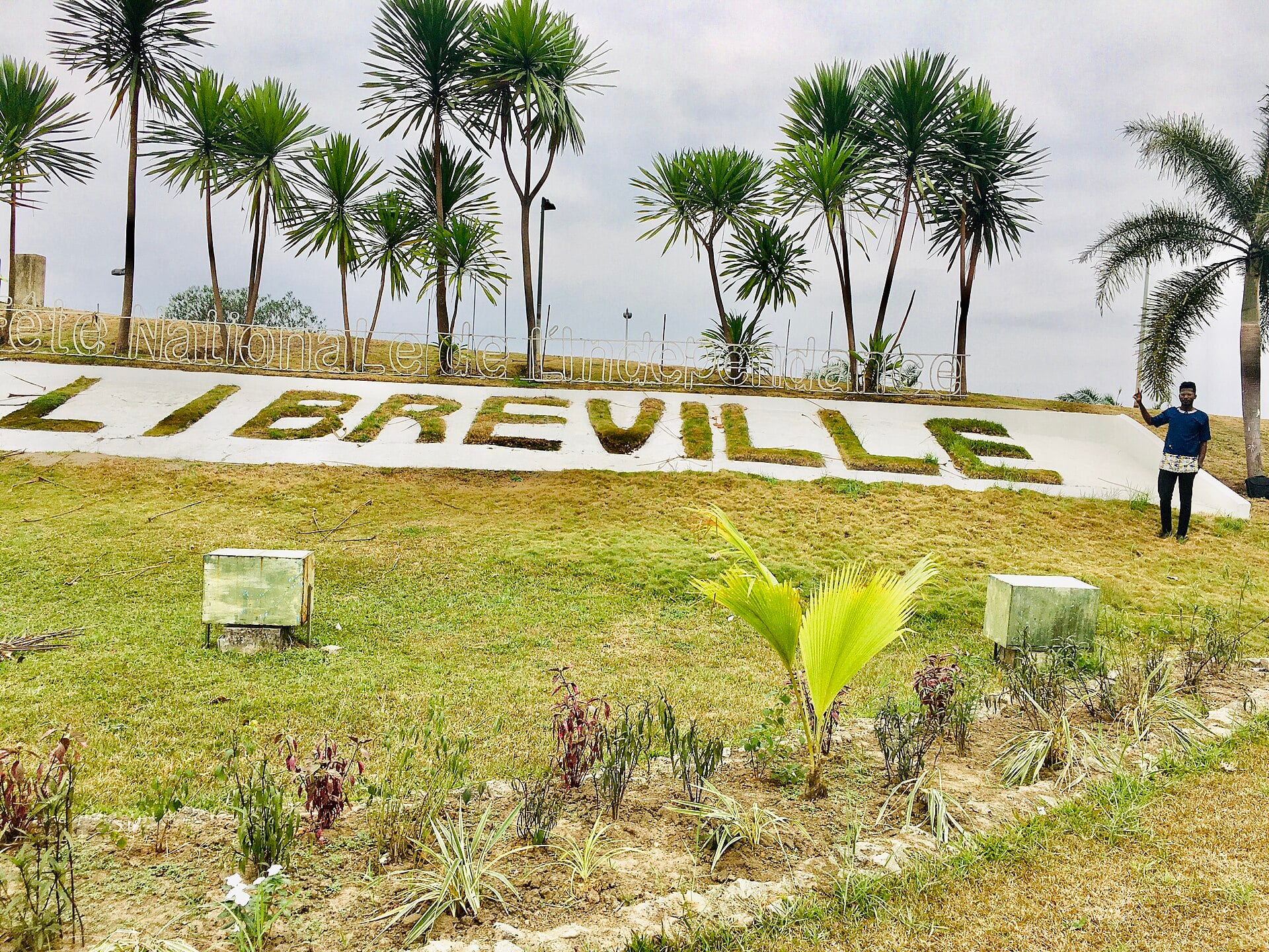 A Libreville sign set into a grassy slope lined with palm trees in Gabon's capital