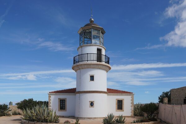 White lighthouse tower with a red-tiled keeper's house on Gavdos island, Greece's southernmost inhabited island, under a blue sky