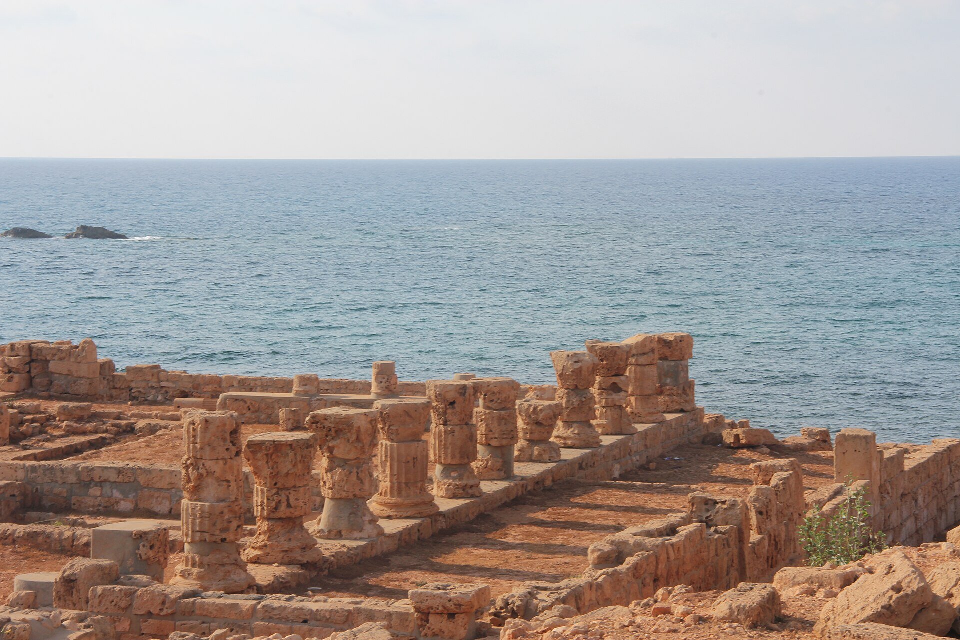 Ruined stone columns of the ancient port of Apollonia beside the blue Mediterranean Sea on Libya's coast