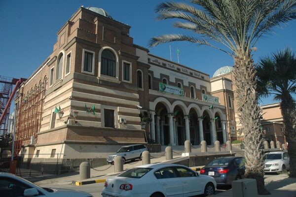 Brick head office of the Central Bank of Libya in Tripoli with arched colonnade, palm trees and parked cars