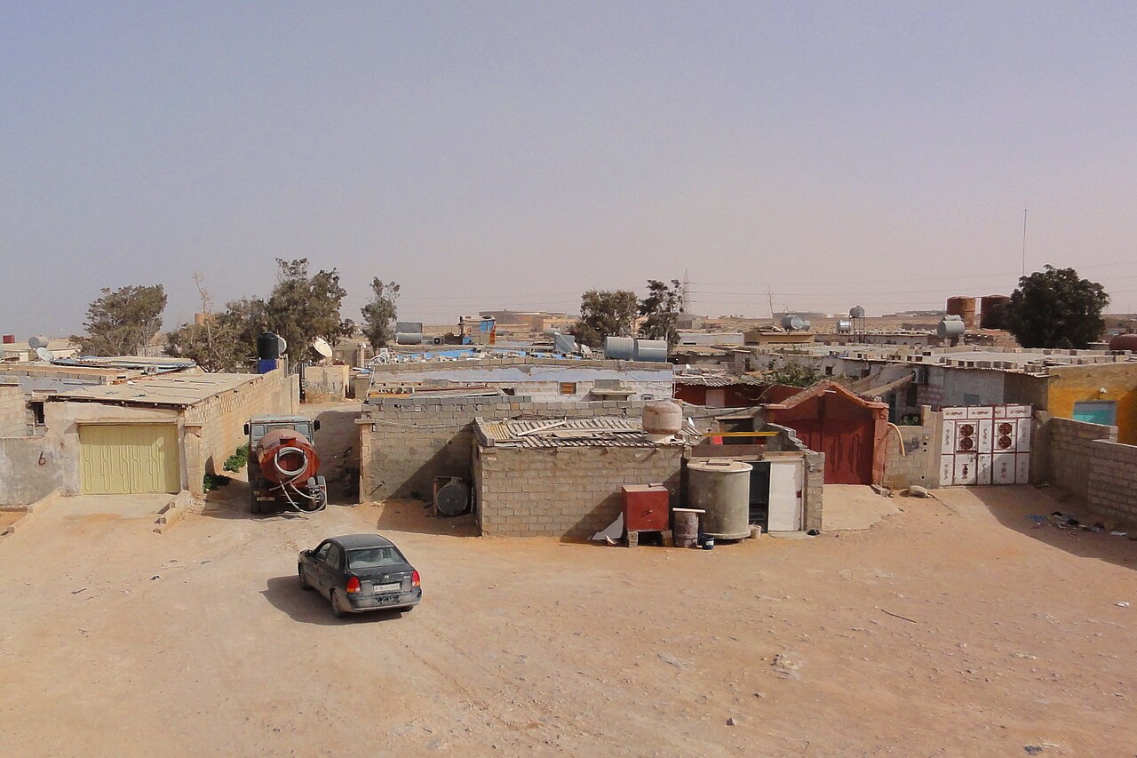 Low houses, water tanks and a parked car on a sandy street in Tobruk, eastern Libya