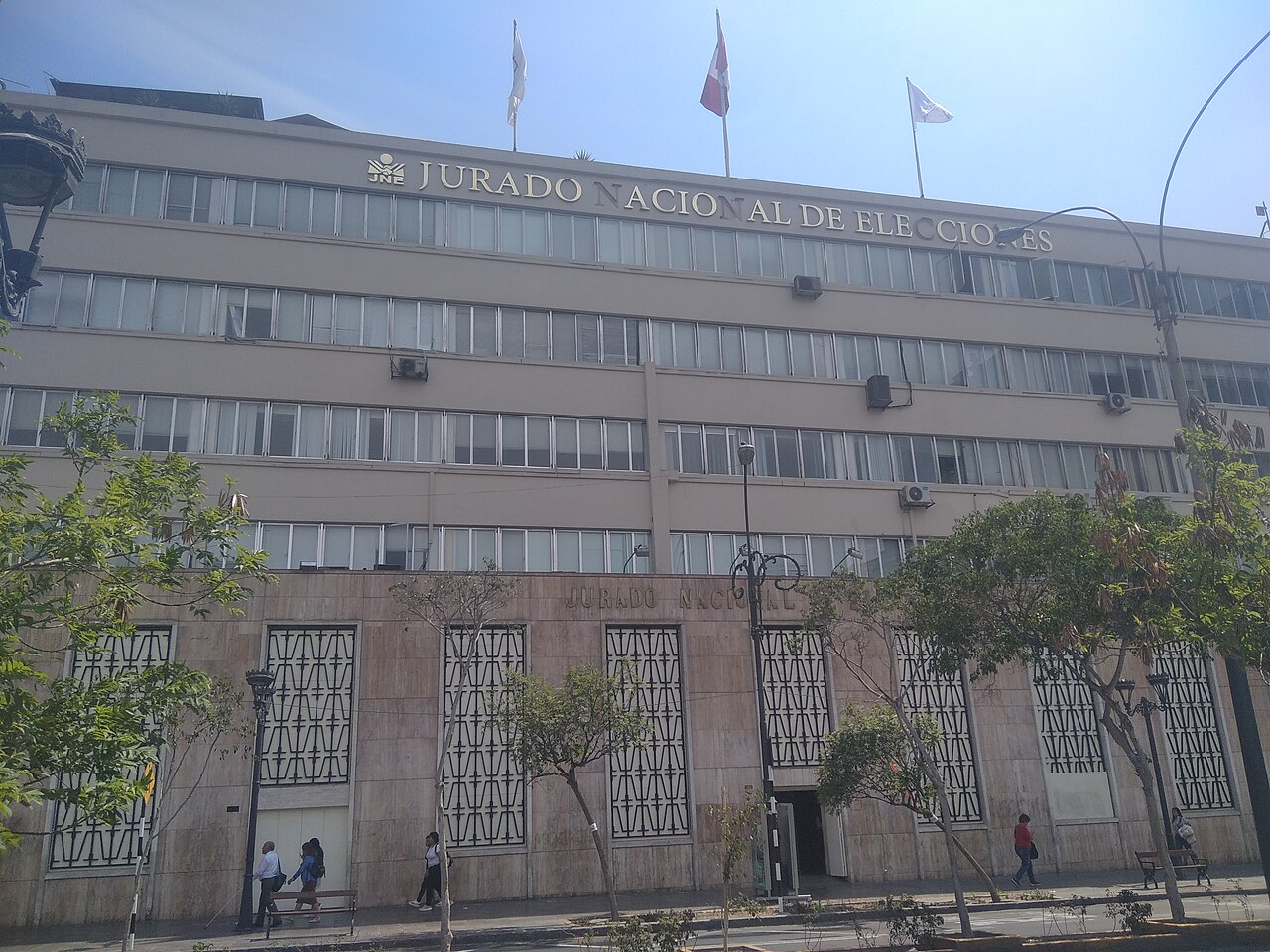 Front facade of the National Elections Jury building in Lima with the words Jurado Nacional de Elecciones above its windows and the Peruvian flag on top