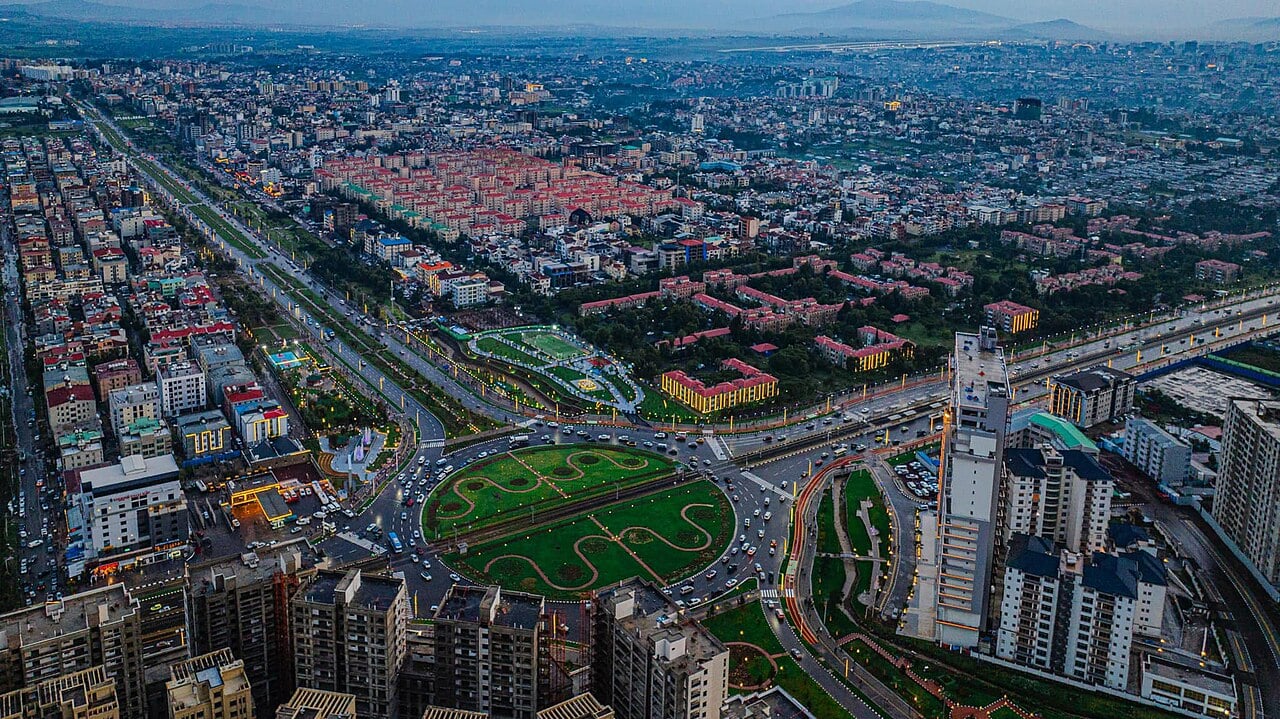 Aerial view of Addis Ababa at dusk with apartment blocks, a roundabout garden and lit avenues