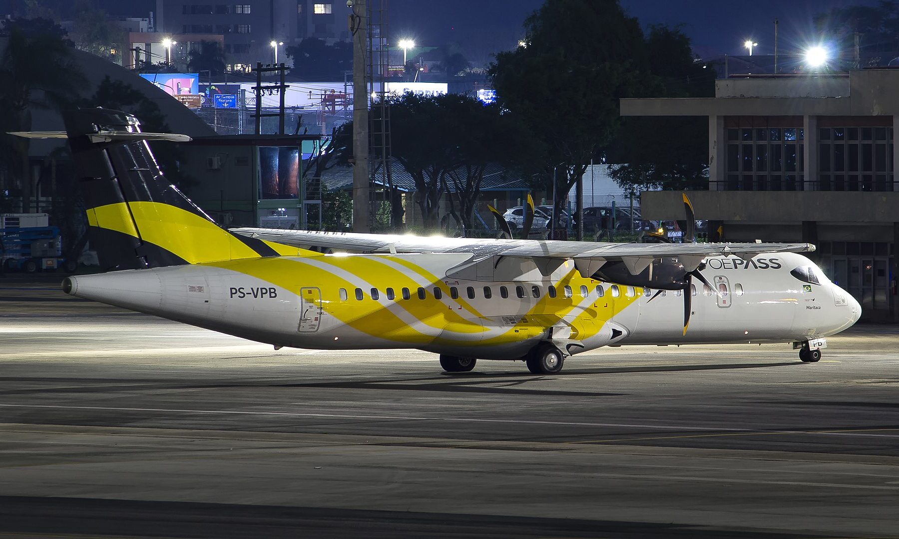 A white ATR 72-500 turboprop with yellow tail livery and VOEPASS titles, registration PS-VPB, parked on an airport apron at night