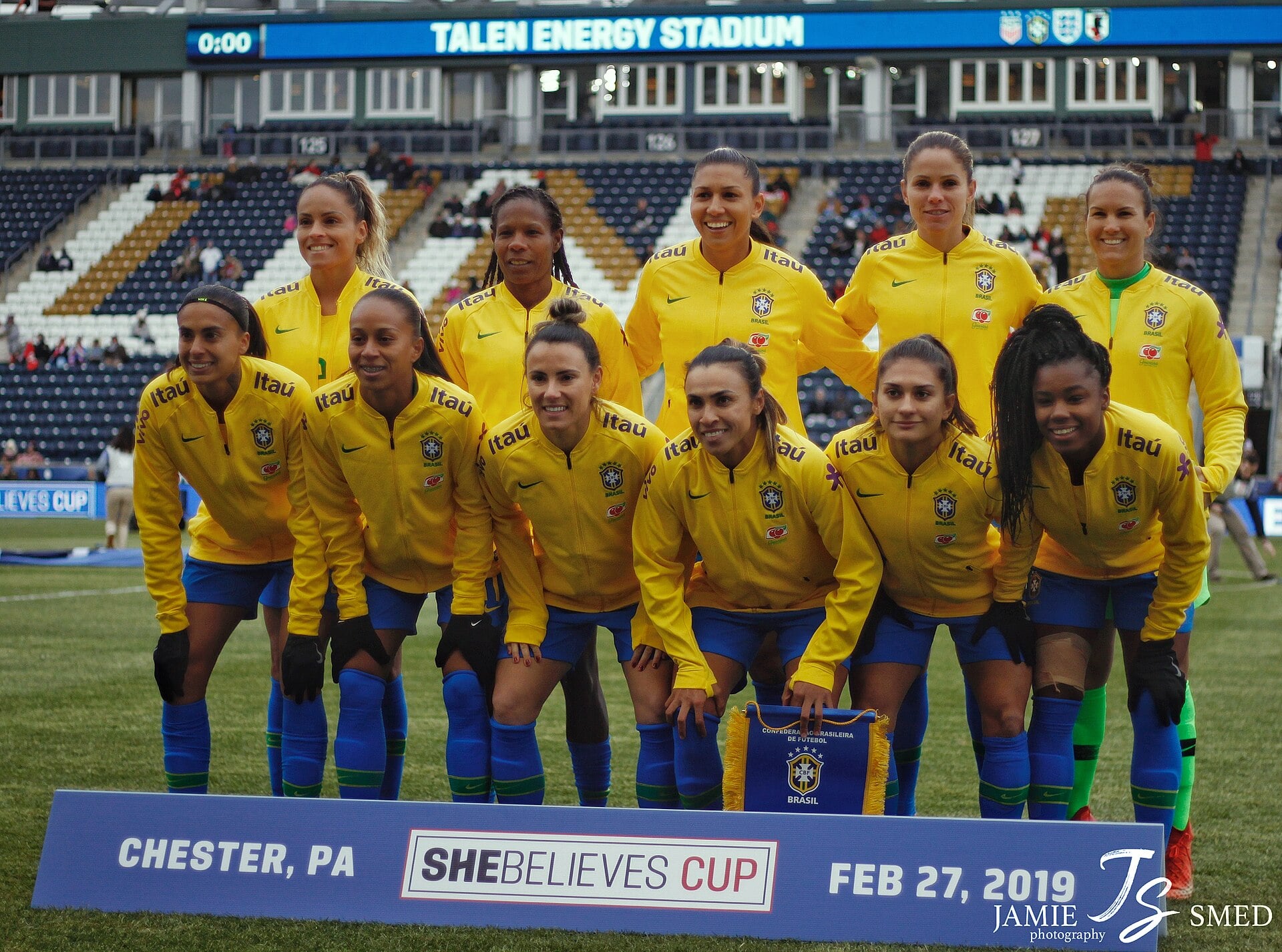 Eleven Brazil women's national team players in yellow jerseys posing for a team photo on the pitch at a SheBelieves Cup match in Chester, Pennsylvania