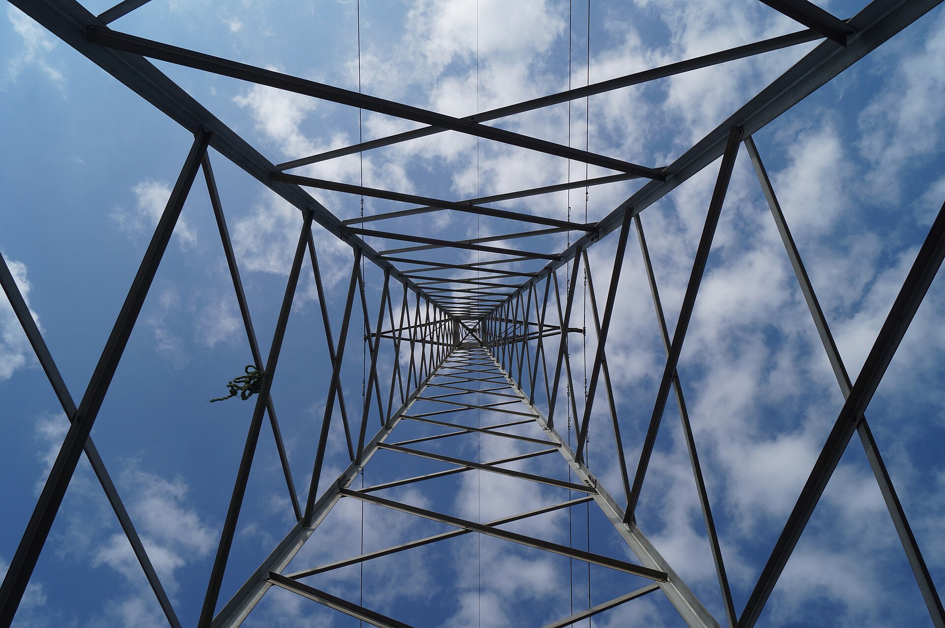 Looking straight up the inside of a steel lattice electricity transmission tower against a blue sky with white clouds, near Maracaibo in Zulia state