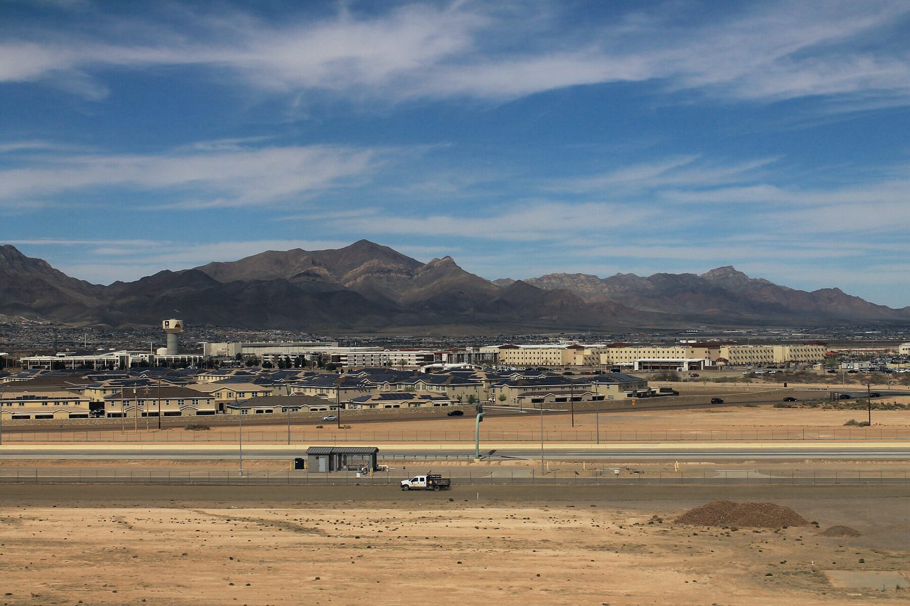 Rows of low buildings at Fort Bliss, Texas, with desert and the Franklin Mountains behind, seen from beside El Paso airport