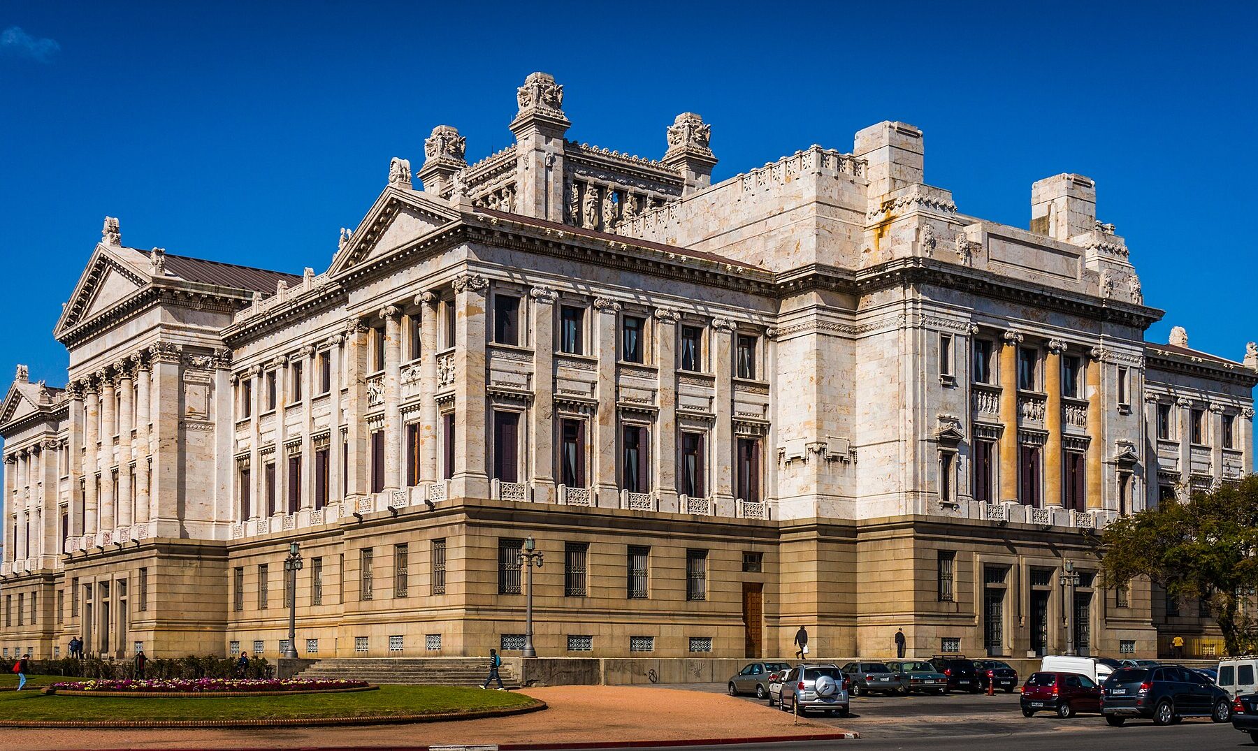 The white marble Legislative Palace in Montevideo under a clear blue sky, with cars parked in front
