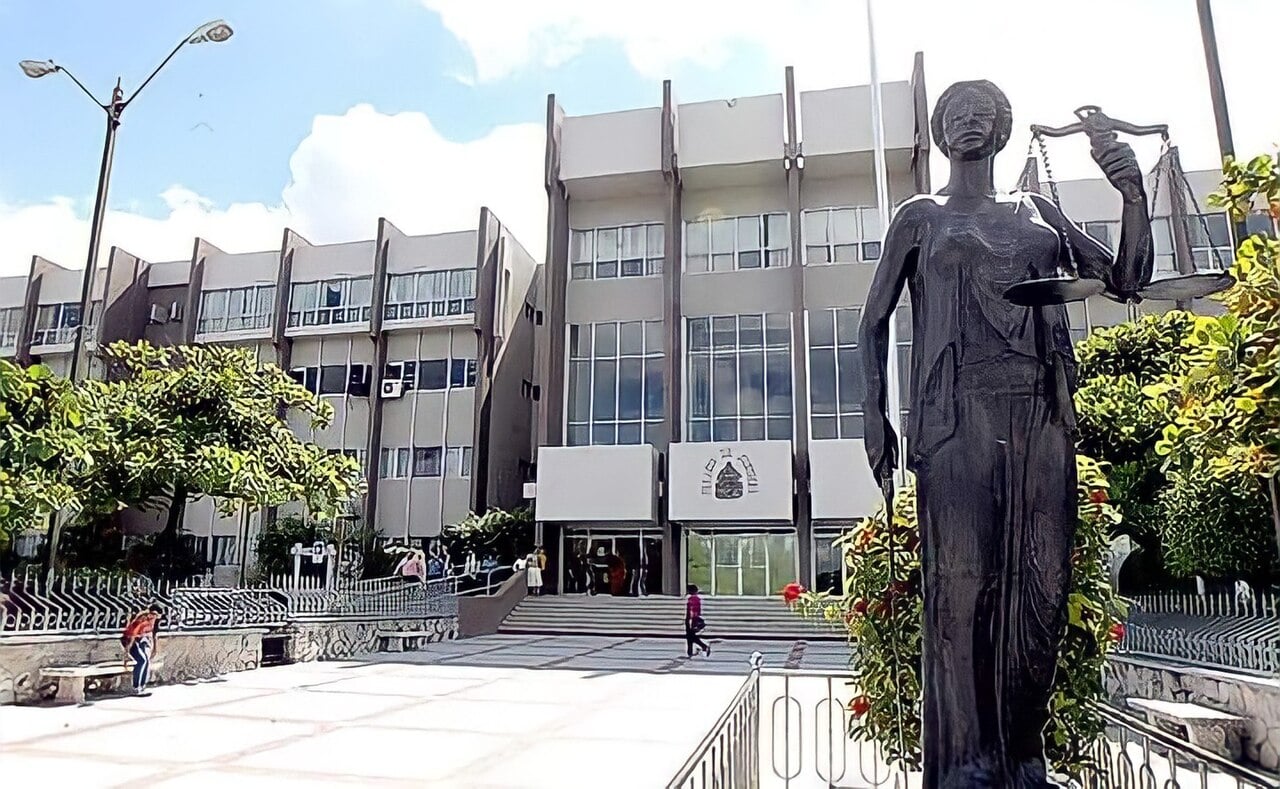 Grey Supreme Court building in Tegucigalpa with a bronze statue of Lady Justice holding scales in the foreground