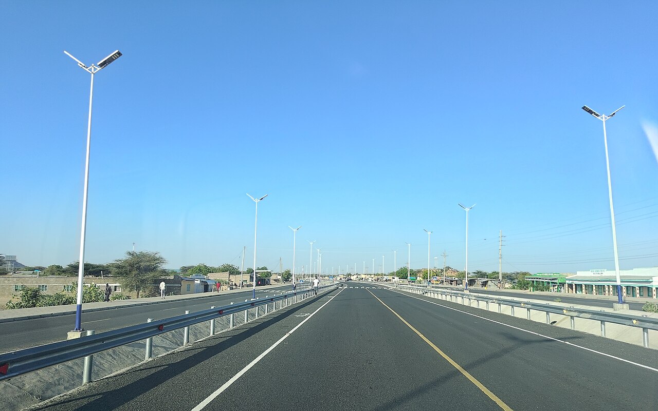 A paved road lined with solar street lights runs through the town of Lokichar under a clear blue sky