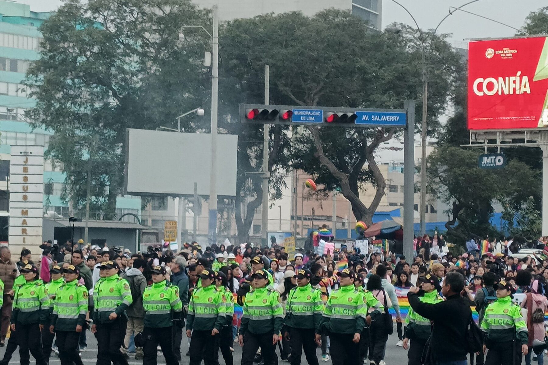 Officers of Peru's National Police in green reflective vests walking along Avenida Salaverry in Lima
