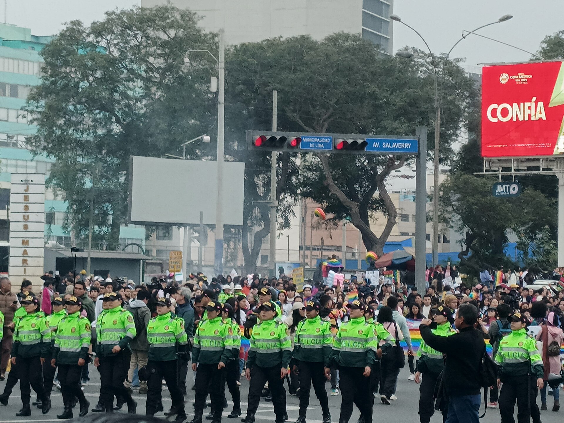 Officers of Peru's National Police in green reflective vests walking along Avenida Salaverry in Lima