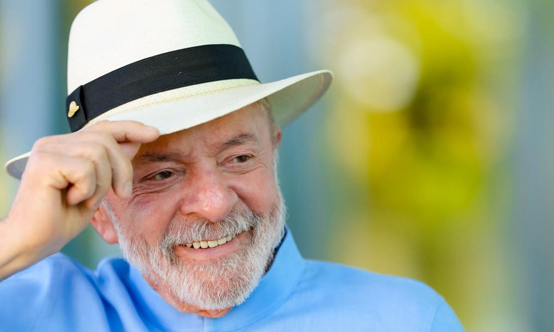 Brazilian President Lula smiling in a white straw hat and light blue shirt