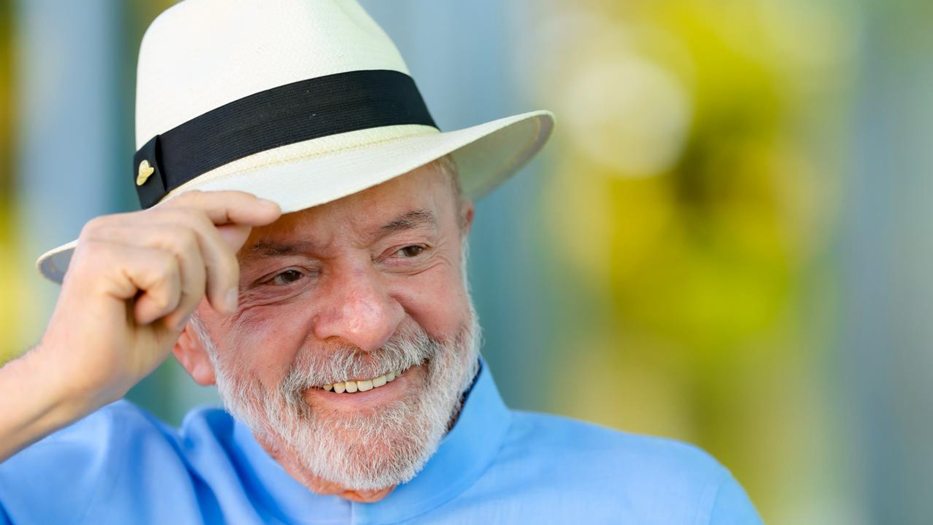 Brazilian President Lula smiling in a white straw hat and light blue shirt