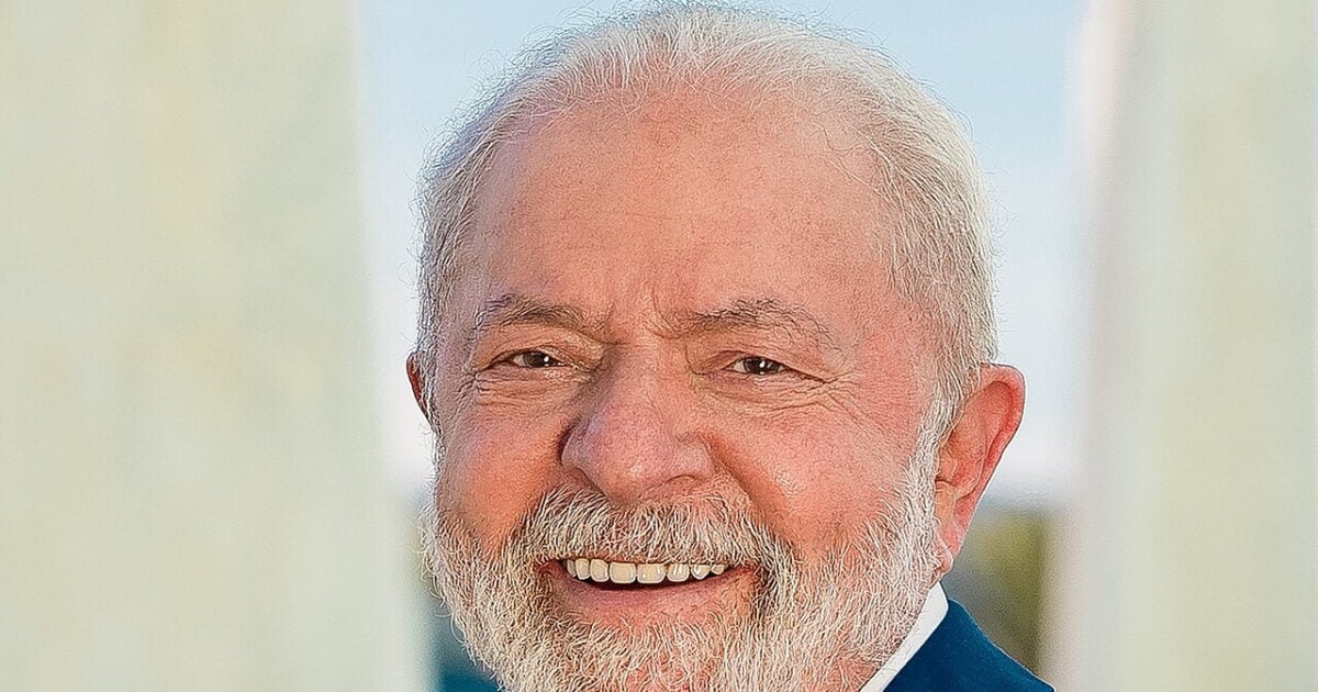Smiling President Lula in a dark blue suit wearing the green and yellow presidential sash