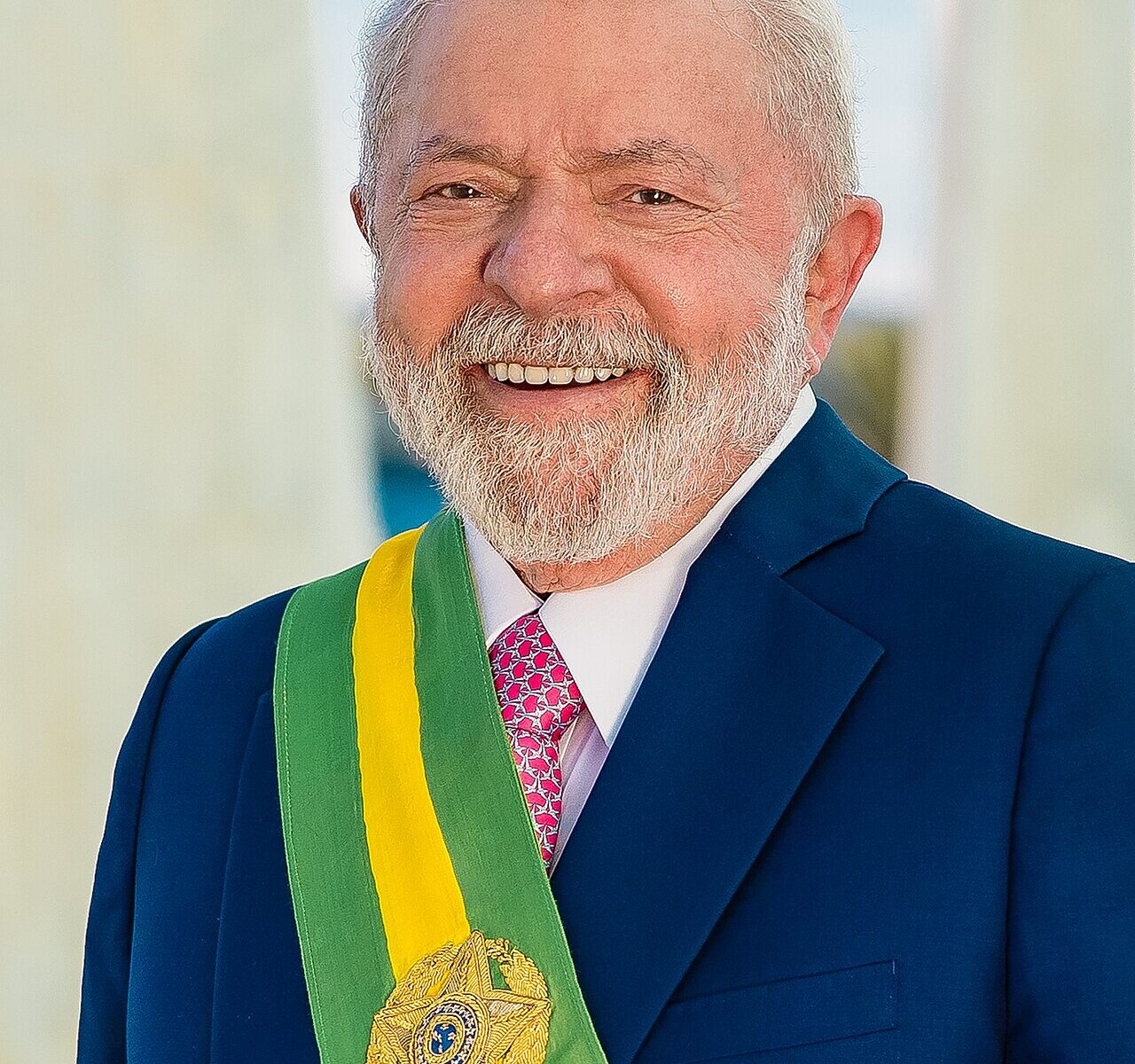 Smiling President Lula in a dark blue suit wearing the green and yellow presidential sash
