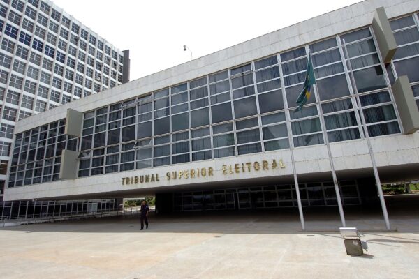 A white modernist building with large glass windows, a Brazilian flag and the words Tribunal Superior Eleitoral on the facade