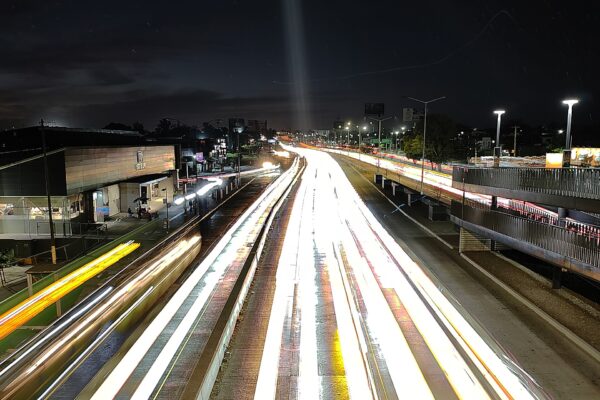 Long-exposure night photo of Periférico Norte in Zapopan, Jalisco, with streaks of car lights beside a bus rapid transit station