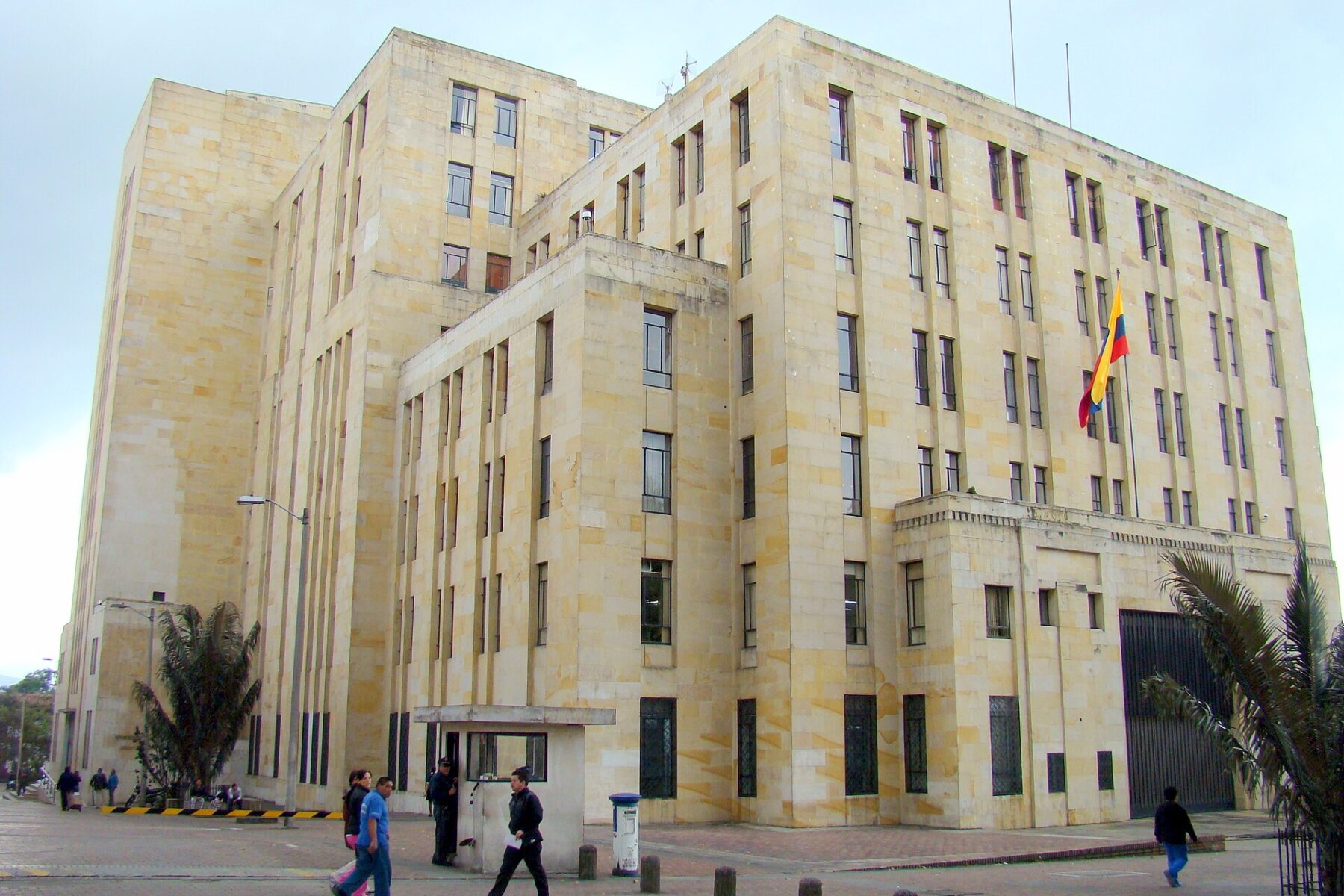 Sandstone headquarters of Colombia's Ministry of Finance and Public Credit in Bogotá with the Colombian flag and pedestrians in front