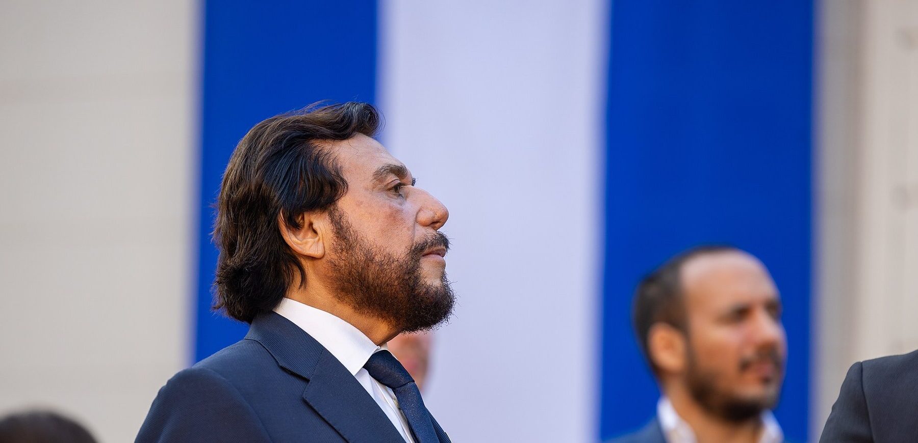 El Salvador's Vice President Félix Ulloa in a dark suit, seen in profile in front of a blue and white backdrop