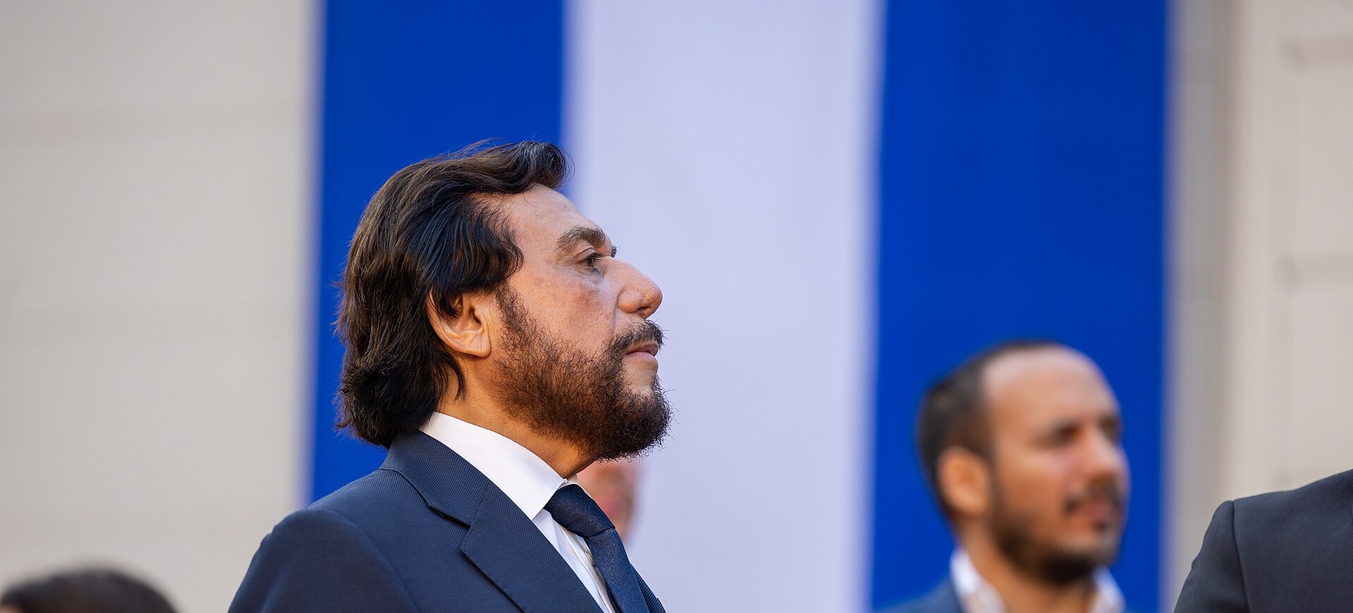 El Salvador's Vice President Félix Ulloa in a dark suit, seen in profile in front of a blue and white backdrop