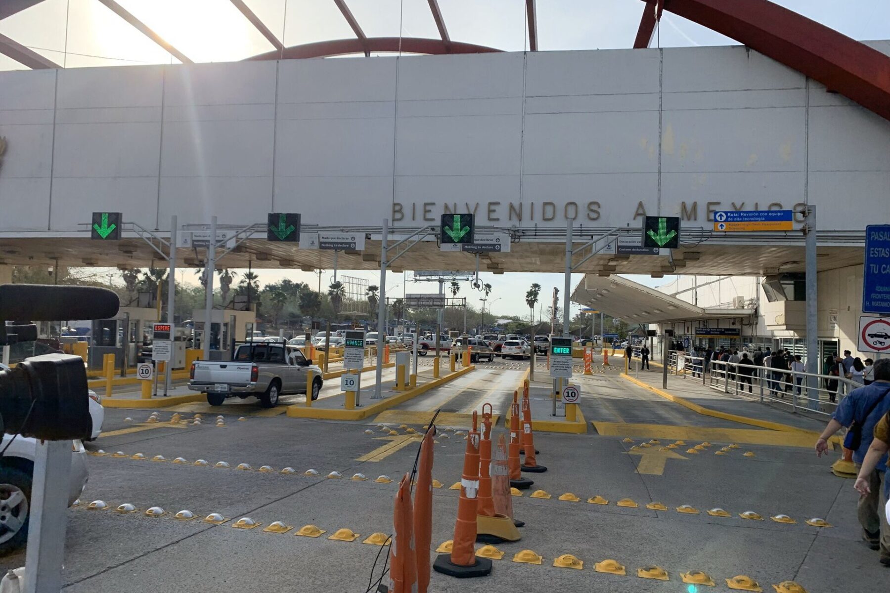 Vehicle lanes, traffic cones and a large Bienvenidos a México sign at the Mexican entry point in Matamoros, under the arches of the port building