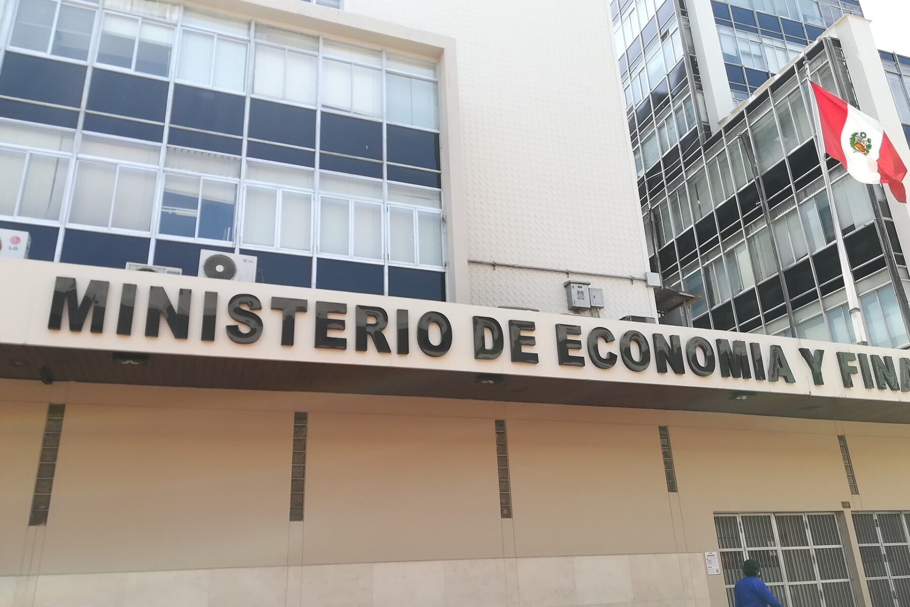 Facade of the Ministry of Economy and Finance building in Lima with its name in large letters and a Peruvian flag
