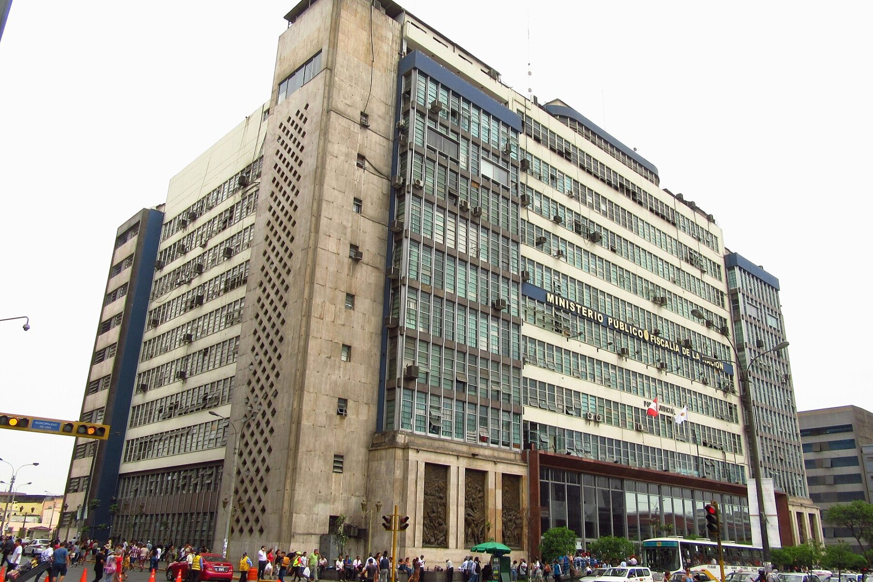 Tall concrete and glass office building with the lettering Ministerio Público Fiscalía de la Nación above a busy street corner with pedestrians in central Lima