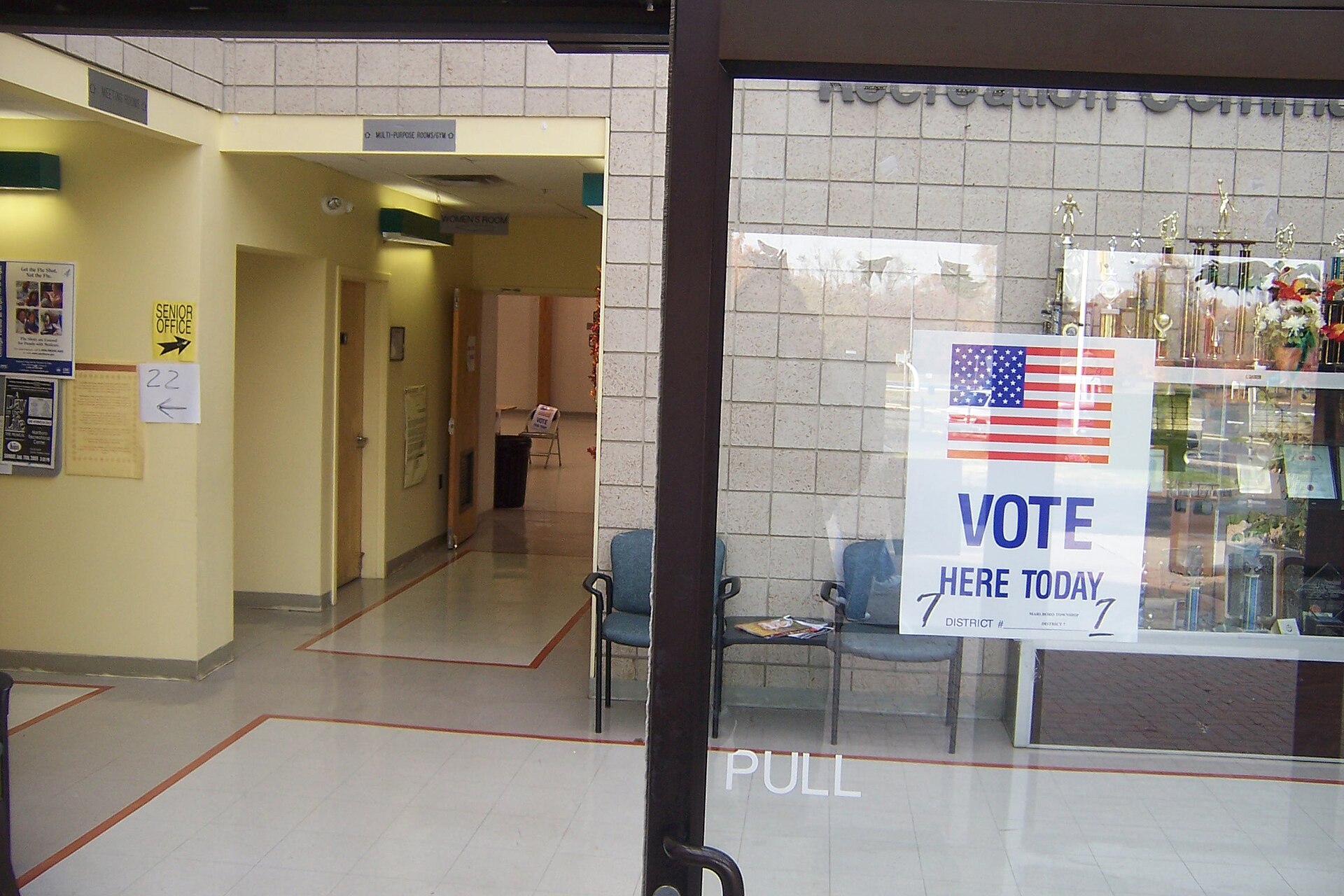 A Vote Here Today sign printed with a US flag on a glass door at the entrance of a recreation centre in New Jersey
