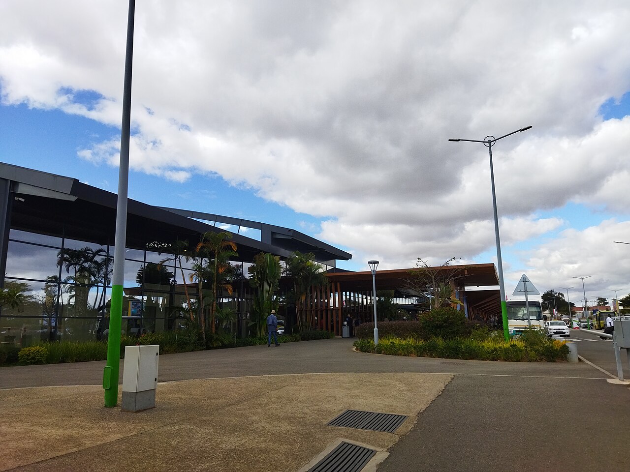 Glass-fronted passenger terminal at Ivato international airport near Antananarivo, with palms and a cloudy sky