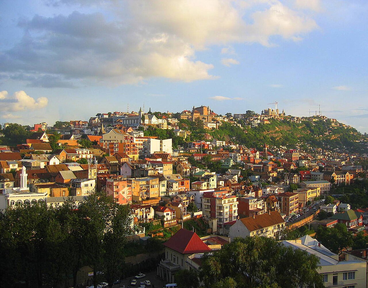Hillside of Antananarivo, Madagascar, with red-roofed houses and apartment blocks climbing to the old upper town under a partly cloudy sky