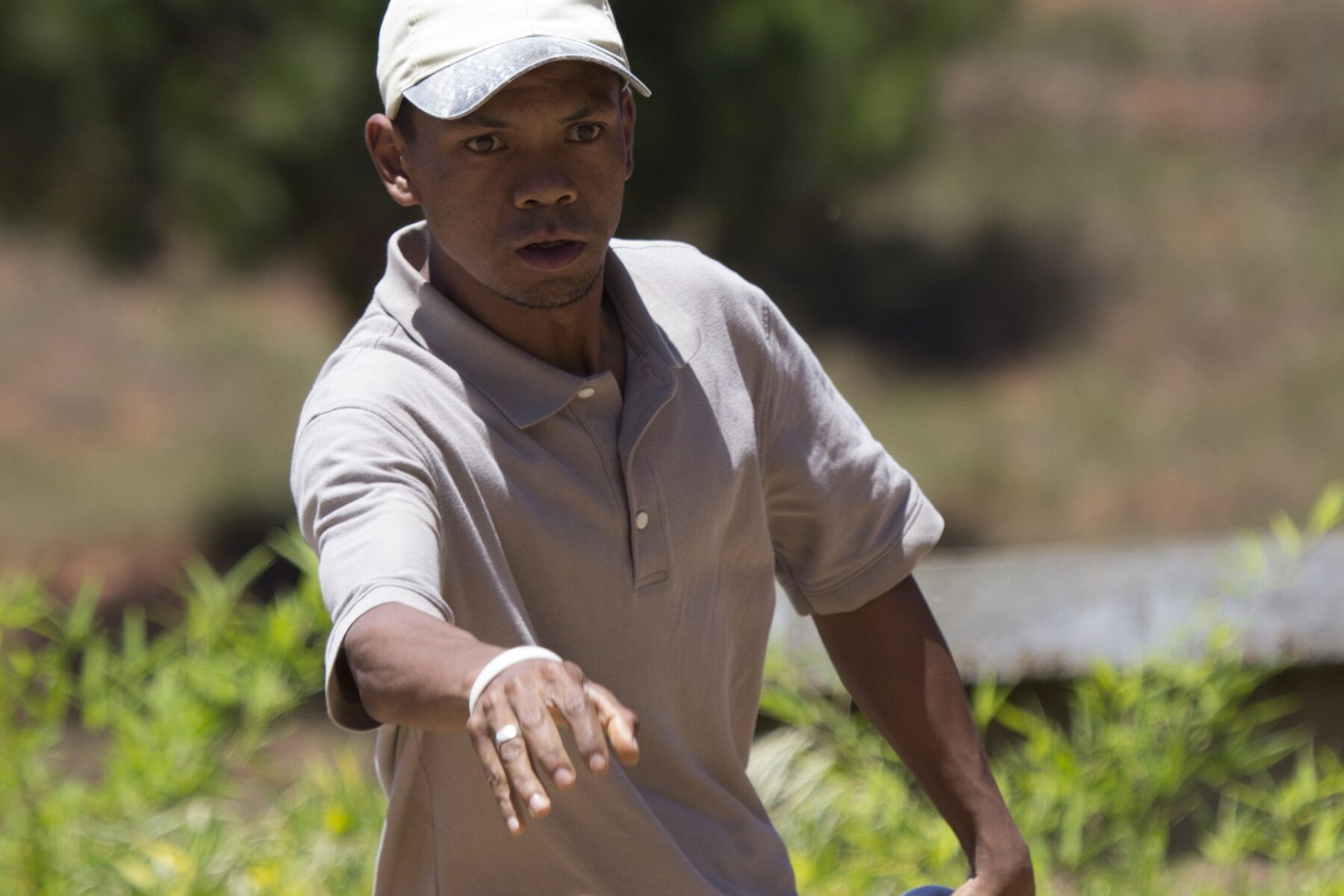 A Madagascar pétanque player in mid-throw, a boule in each hand, during a match