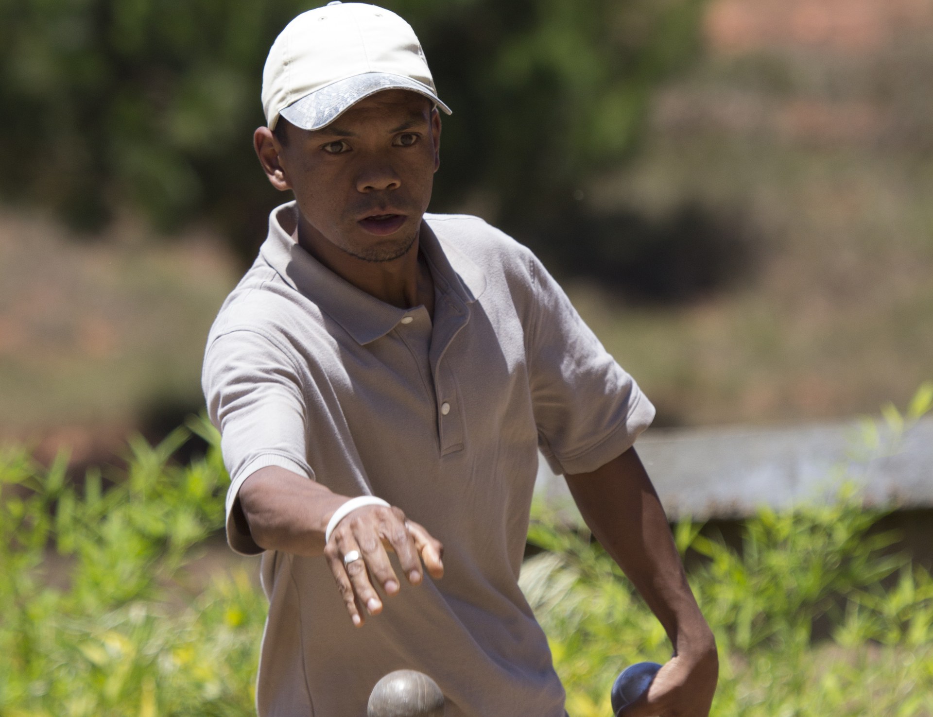 A Madagascar pétanque player in mid-throw, a boule in each hand, during a match