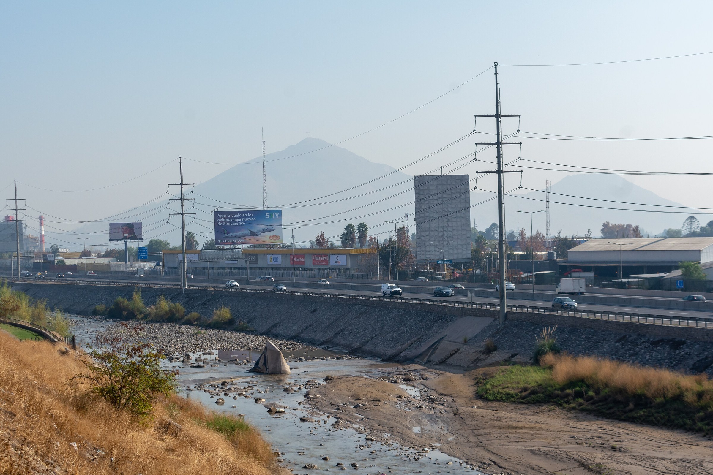 A motorway and river channel in Renca, a district of Santiago, Chile, with hills behind