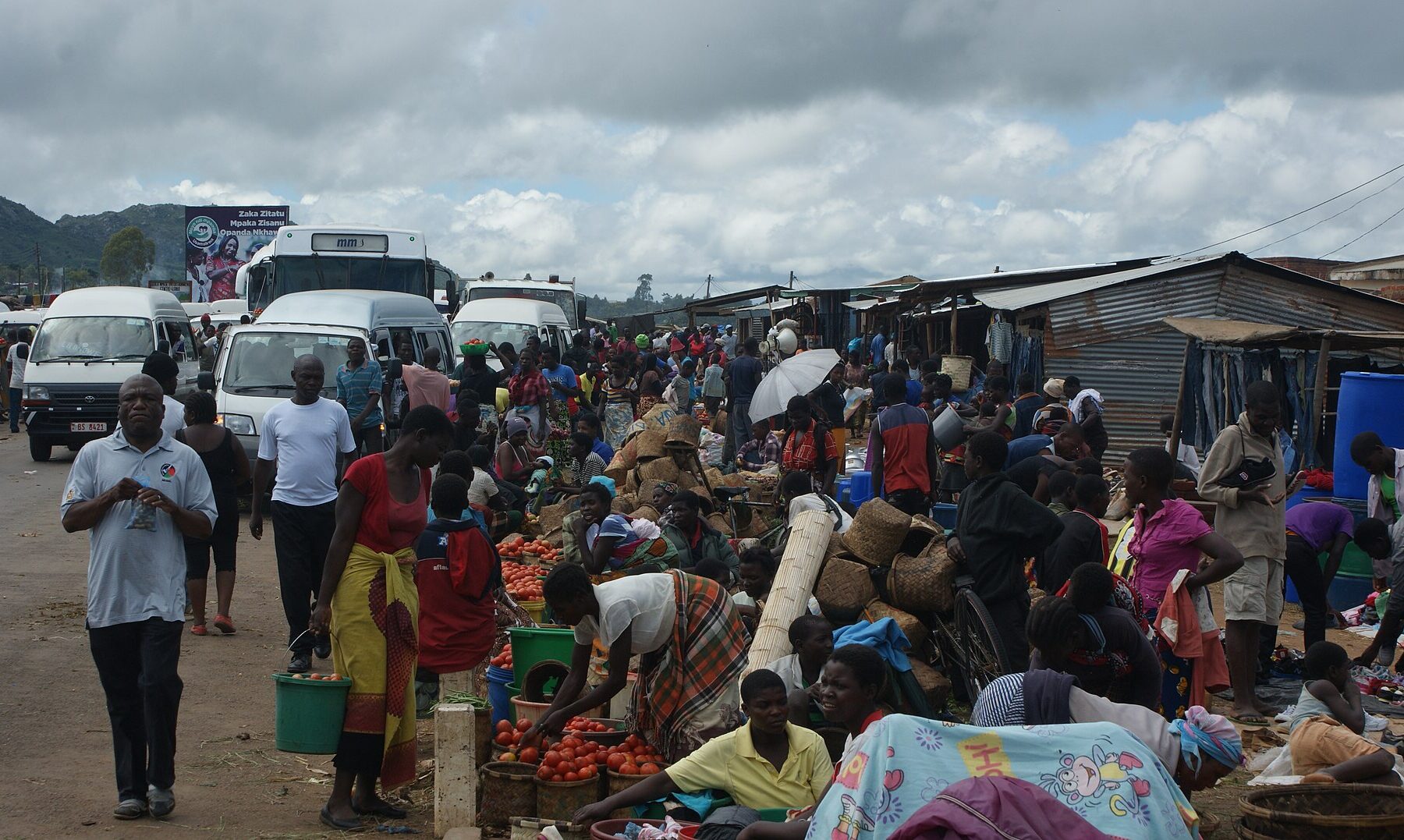 Traders sell tomatoes and farm produce from baskets and buckets beside minibuses at the crowded Lizulu market in Malawi