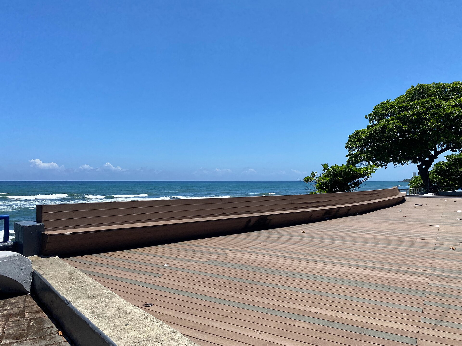 Wooden boardwalk with a long built-in bench on the Malecón promenade in Santo Domingo, facing the Caribbean Sea