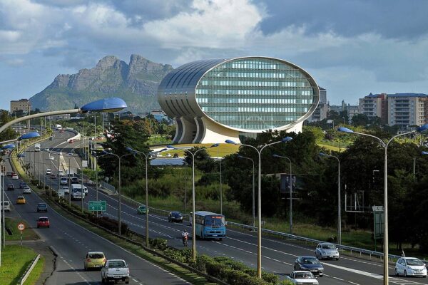 Oval glass office building beside a busy highway with a rocky mountain behind, Ebene Cybercity, Mauritius